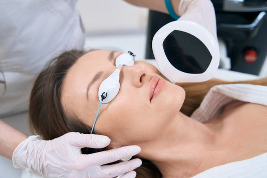 Woman receiving laser skin treatment with protective eye pads in a spa or clinic setting