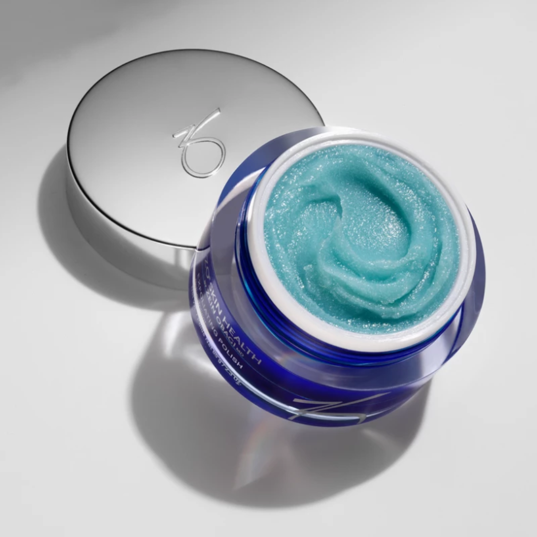 Open blue jar of exfoliating polish with silver lid on white background